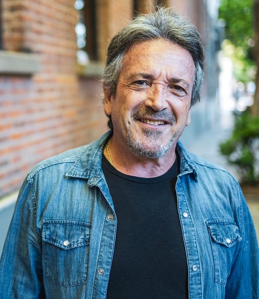 Man in denim jacket in front of brick building